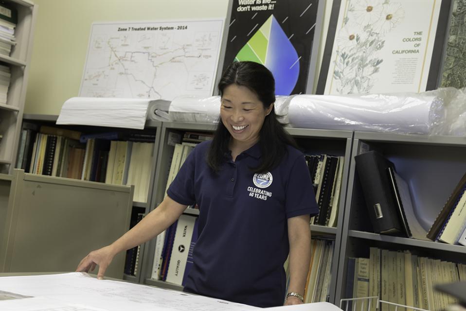 Zone 7 Employee smiling and reviewing project blueprints in an office