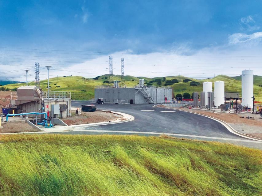 Water treatment plant surrounded by grassy hills.