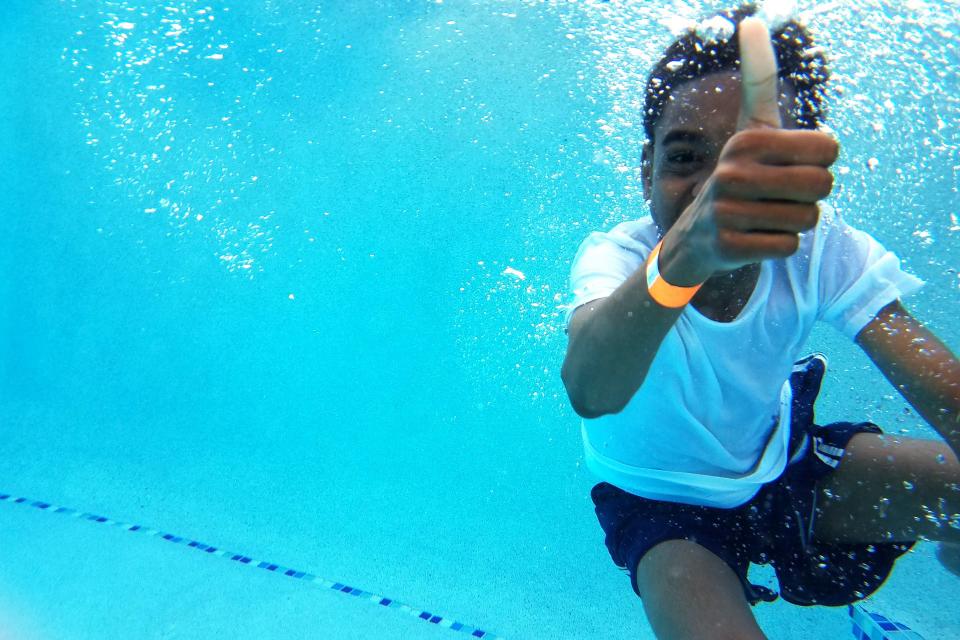Kid giving a thumbs up while swimming