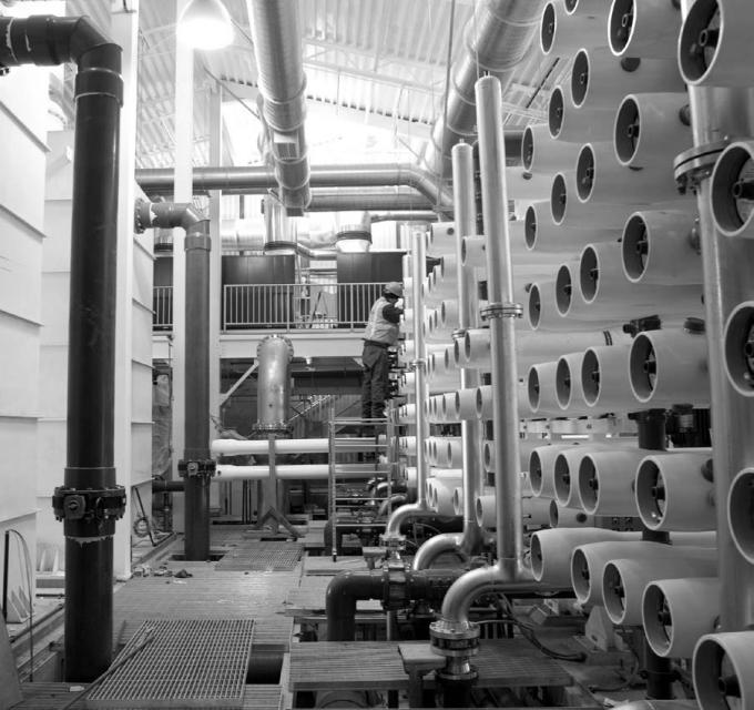 Ends of large pipes line a right wall with a maintenance worker inspecting the pipes
