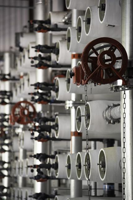 Close up of the ends of white pipes accompanied by red wheels used for reverse osmosis.