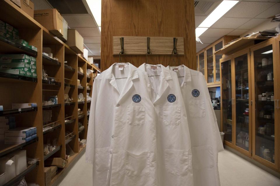 Three lab coats hanging in a locker room